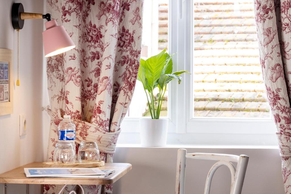 a table with a lamp and a window at Hôtel de Lion sur Mer in Lion-sur-Mer