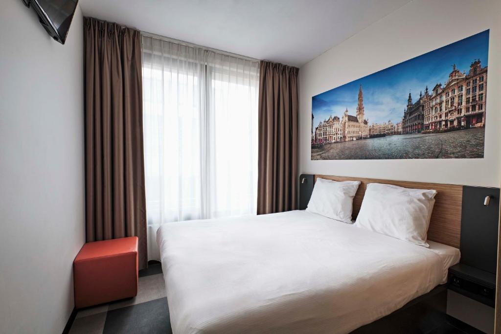 a bedroom with a white bed and a large window at easyHotel Brussels City Centre in Brussels