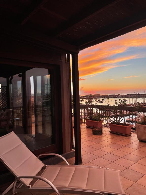 Attico con terrazza sul porticciolo turistico di Vibo Marina في فيبو فالينتيا مارينا: شرفة مع كراسي وإطلالة على غروب الشمس