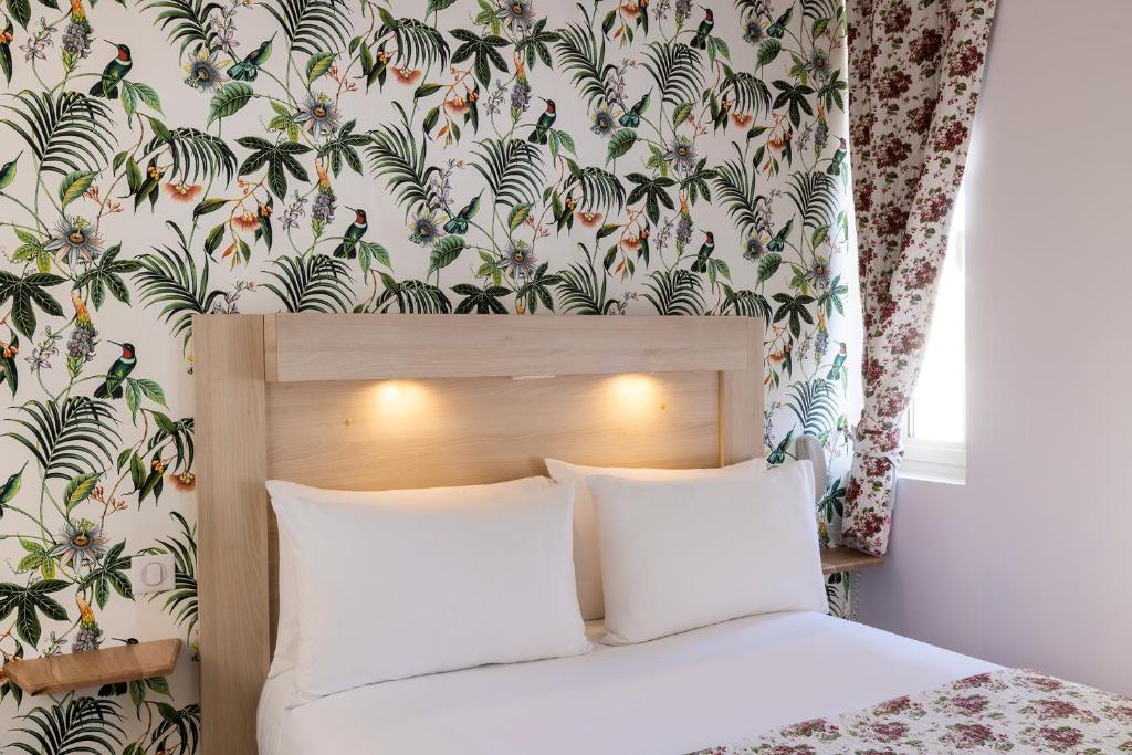 a bedroom with a bed with a floral wallpaper at Hôtel de Lion sur Mer in Lion-sur-Mer