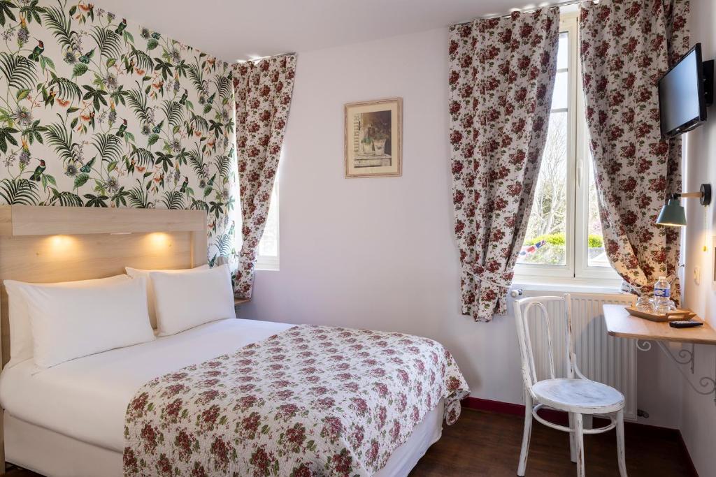 a bedroom with a bed and a desk and a window at Hôtel de Lion sur Mer in Lion-sur-Mer