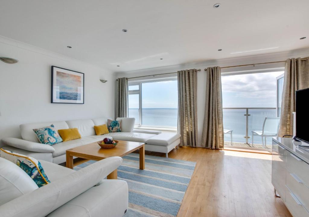 a living room with white furniture and a view of the ocean at Neptune House in Porthleven