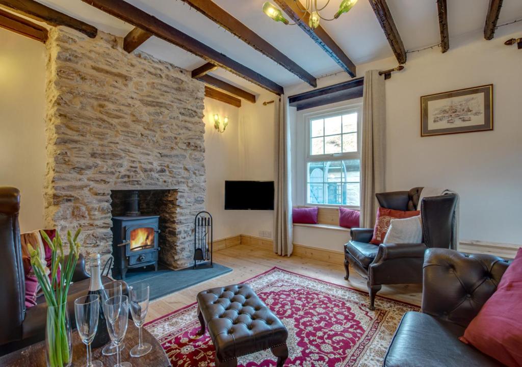 a living room with a stone wall and a fireplace at Auntie Katies Cottage in Looe