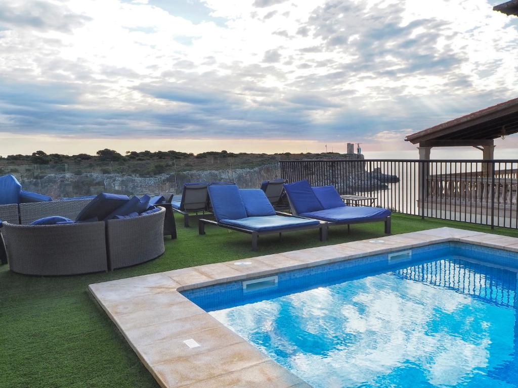 a swimming pool with blue chairs at Hotel Rocamar in Cala Figuera