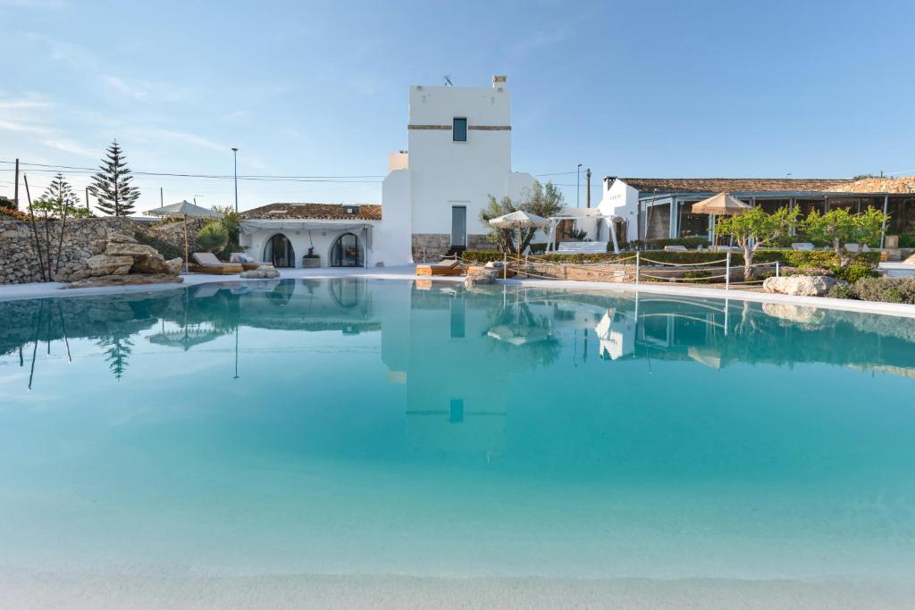 a large pool of blue water in front of a building at Masseria Samenti in Torre Suda