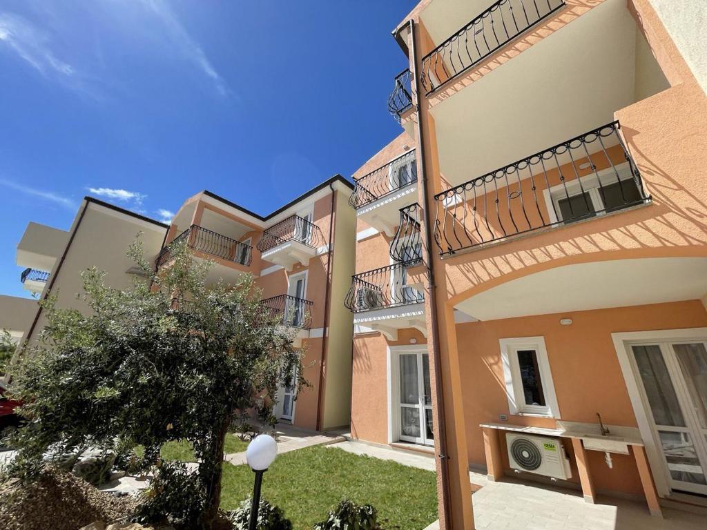 a large apartment building with balconies and a tree at Affittimoderni La Maddalena - MADA03 in La Maddalena