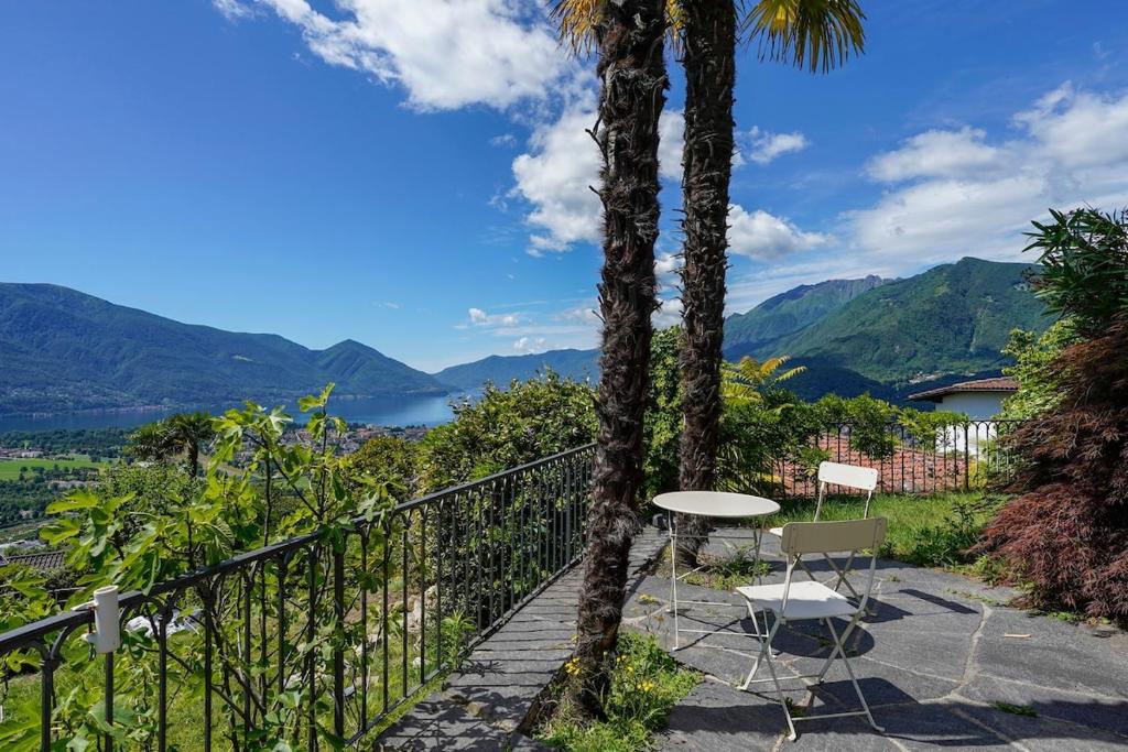 a table and chairs on a balcony with a view at Palm Cottage in Locarno