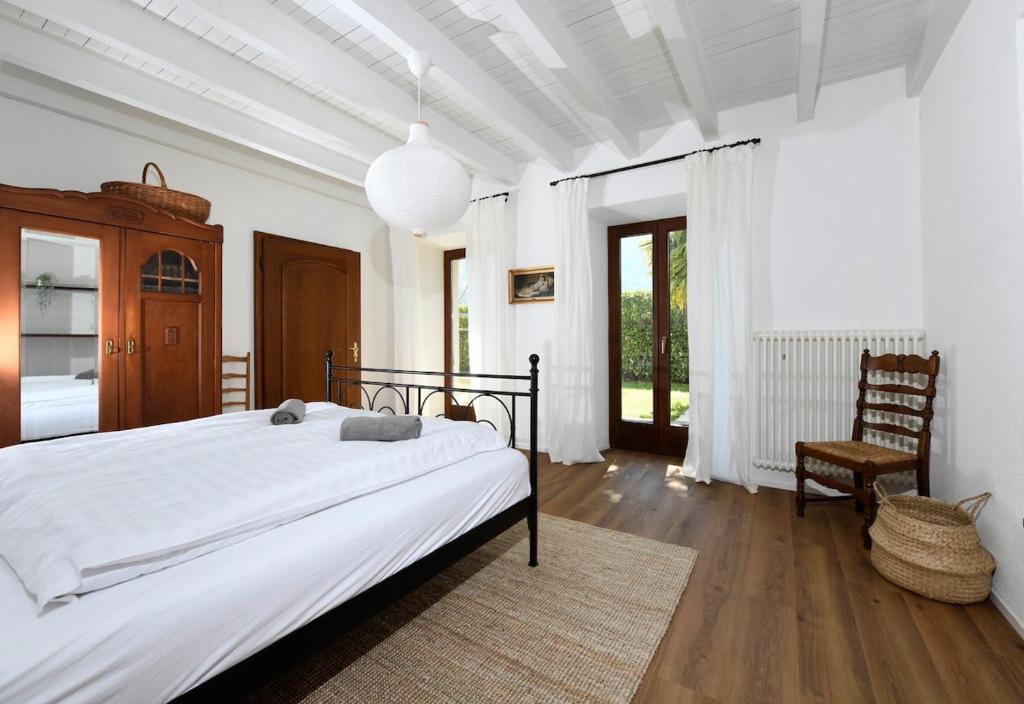 a white bedroom with a large bed and a chair at The Lake Garden 1 in Caslano
