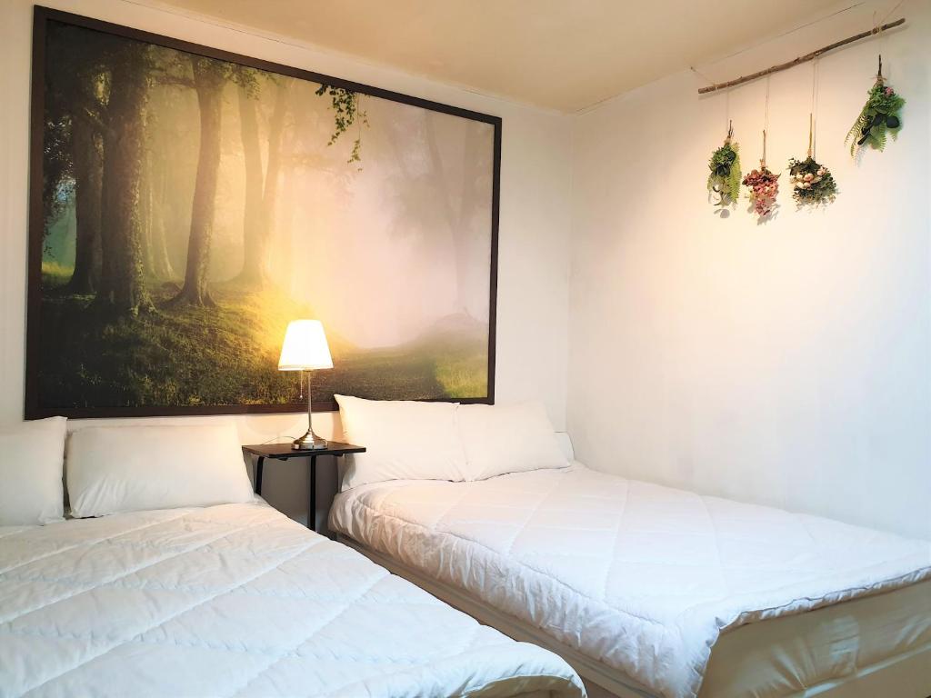 two beds in a room with a painting on the wall at Ewha Hostel in Seoul
