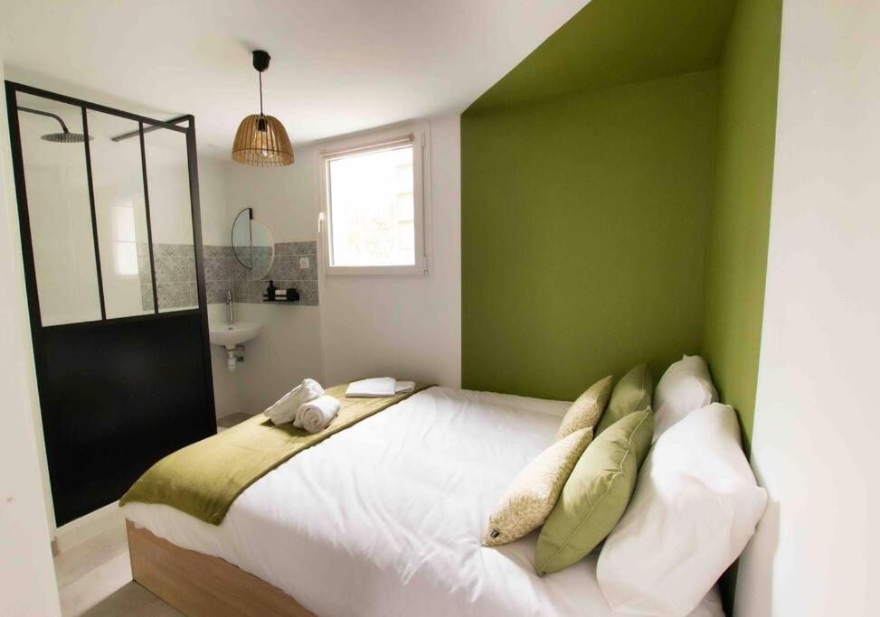 - une chambre avec un grand lit blanc aux murs verts dans l'établissement Apt T2 neuf terrasse, à Arles