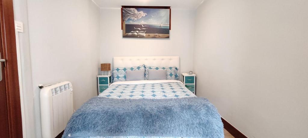 - une petite chambre avec un lit et une couverture bleue dans l'établissement Taraska I & II, à Bermeo