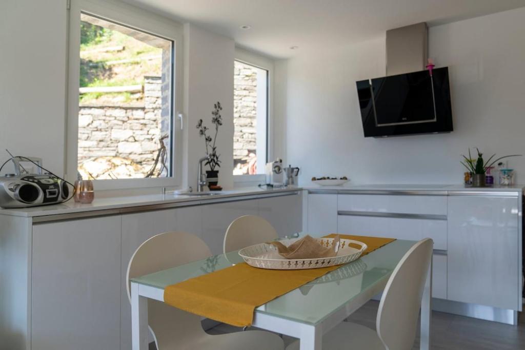 a kitchen with a table and chairs and a tv at Orselina in Style in Orselina