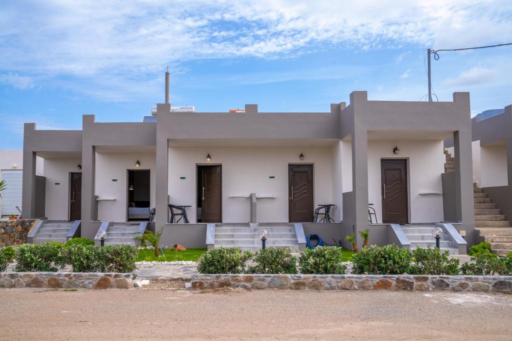 a large white house with stairs and chairs in front at Lafo Rooms in Elafonisi