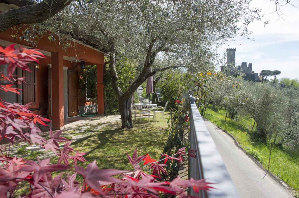 a walkway next to a house with trees and red flowers at Villino La Casetta in Castelnuovo Magra