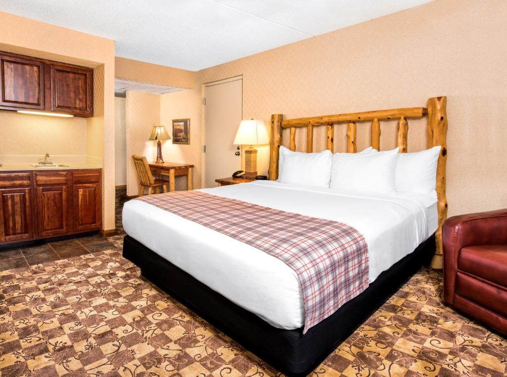 a hotel room with a large bed and a chair at Lodge of the Ozarks in Branson