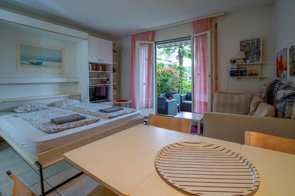 a living room with a bed and a table and a room at Studio by the Pool in Caslano