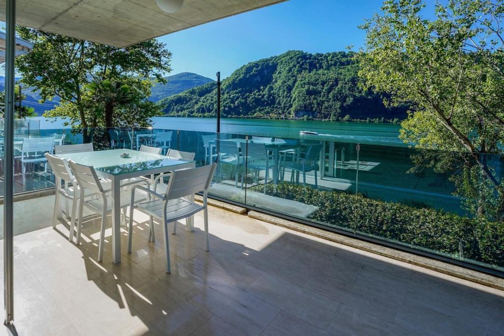 a balcony with a table and chairs and a view of the water at The Glass House & SPA in Caslano