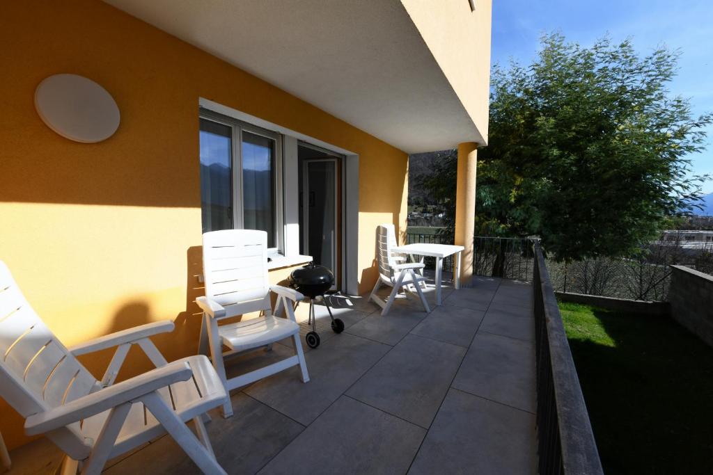 eine Terrasse mit Stühlen und Tischen auf einem Gebäude in der Unterkunft Comfortably Losone in Losone