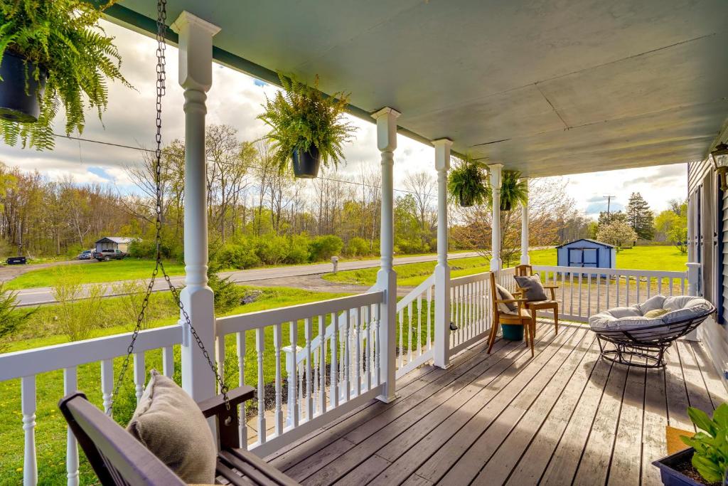 Freeville Home with Covered Porch Near Cayuga Lake! في Freeville: شرفة مع كراسي ومرجيح