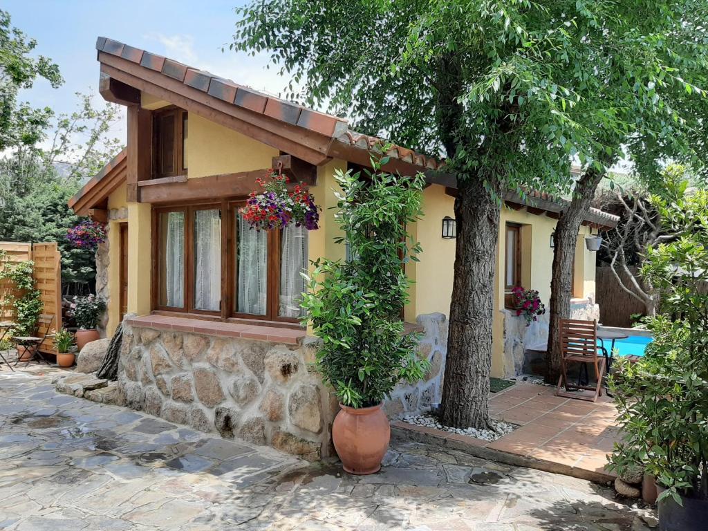 ein kleines Haus mit einem Baum davor in der Unterkunft Acogedora casa rural en la sierra de Madrid in Mataelpino