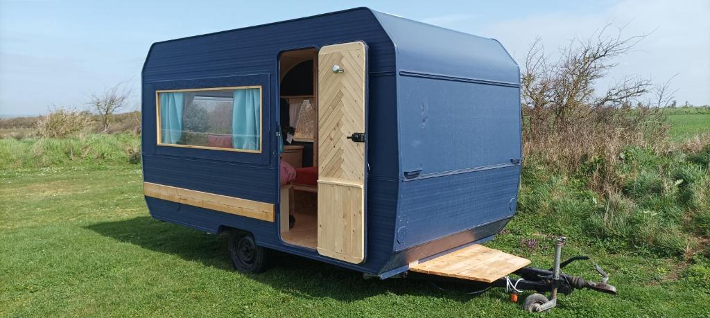 a blue tiny house sitting in the grass at Camping Les Ronds Duval face aux îles anglo-normandes in Les Moitiers-dʼAllonne