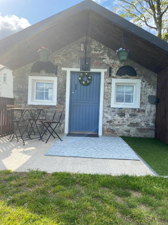 una casa de piedra con una puerta azul y una mesa en The Hen House, 