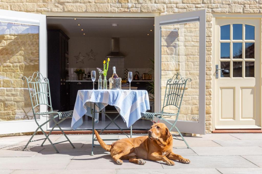 a dog laying next to a table and chairs at Sunflower Cottage in Ampleforth