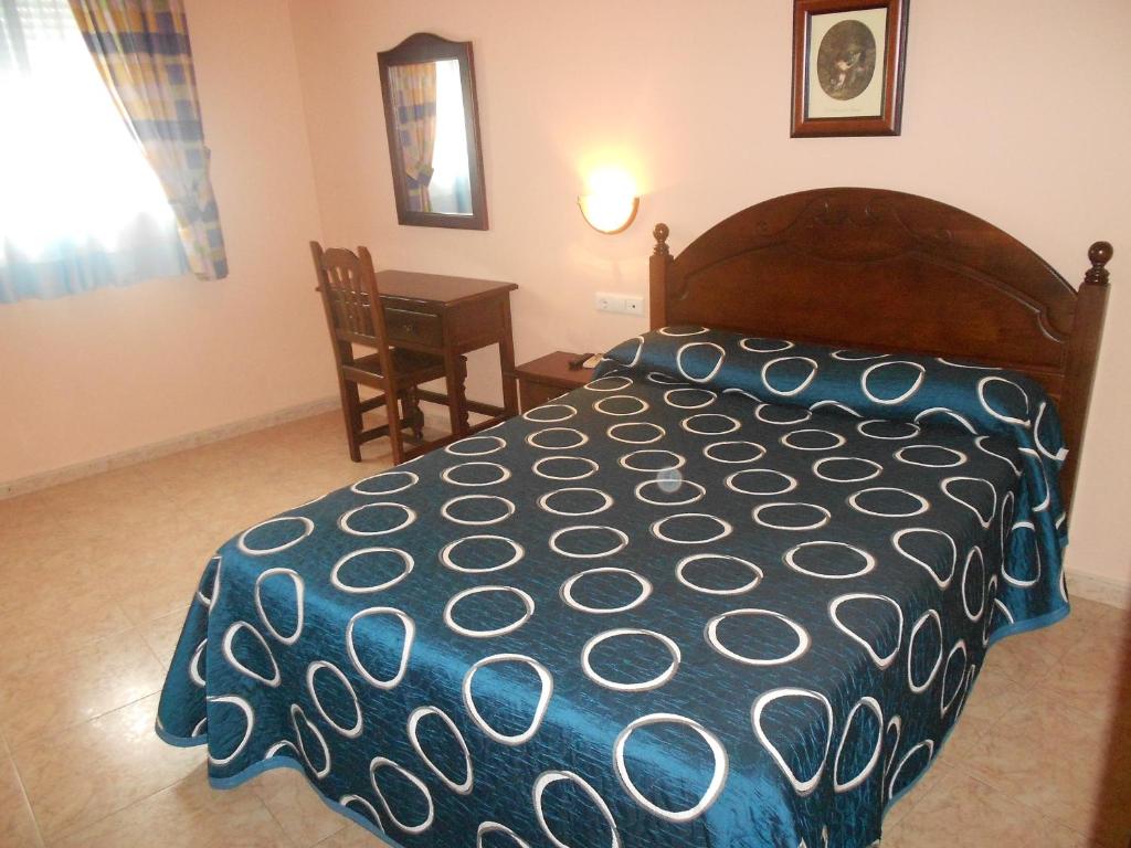 sypialnia z łóżkiem, stołem i krzesłem w obiekcie Hostal El Polígono w mieście Lucena
