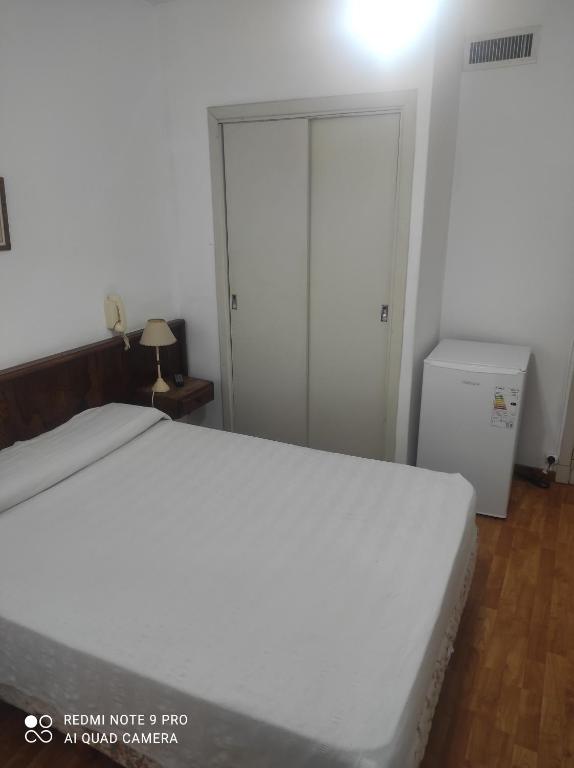 una camera con letto bianco e frigorifero di Necochea Real Hotel a Necochea