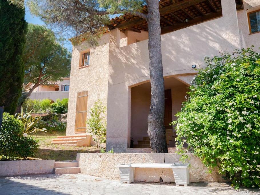 un edificio con un árbol y un banco delante de él en Maison familiale sous les palmiers de Hyères en Hyères