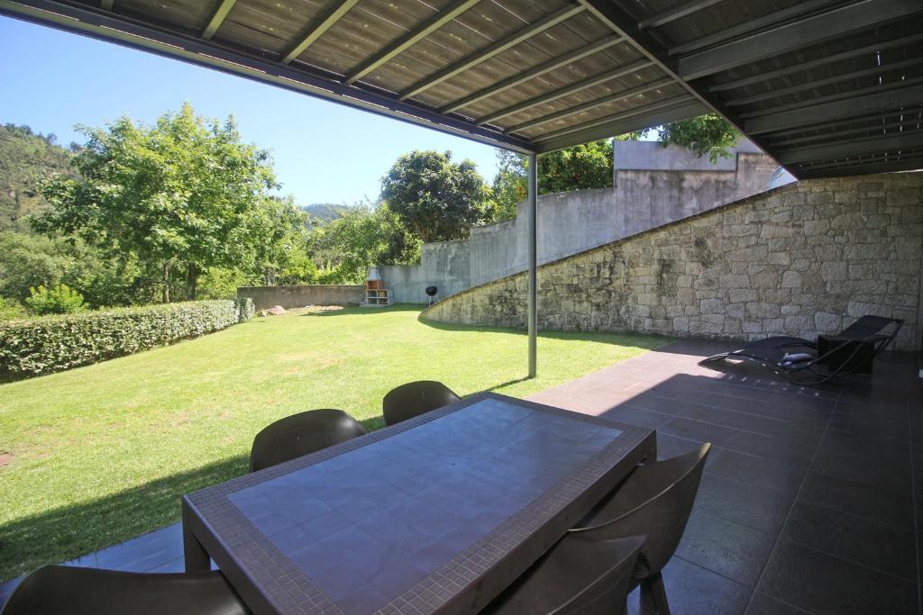 a patio with a table and chairs and a stone wall at Apartamento Corco - Casas Barca do Rio by Gerês Casas in Geres