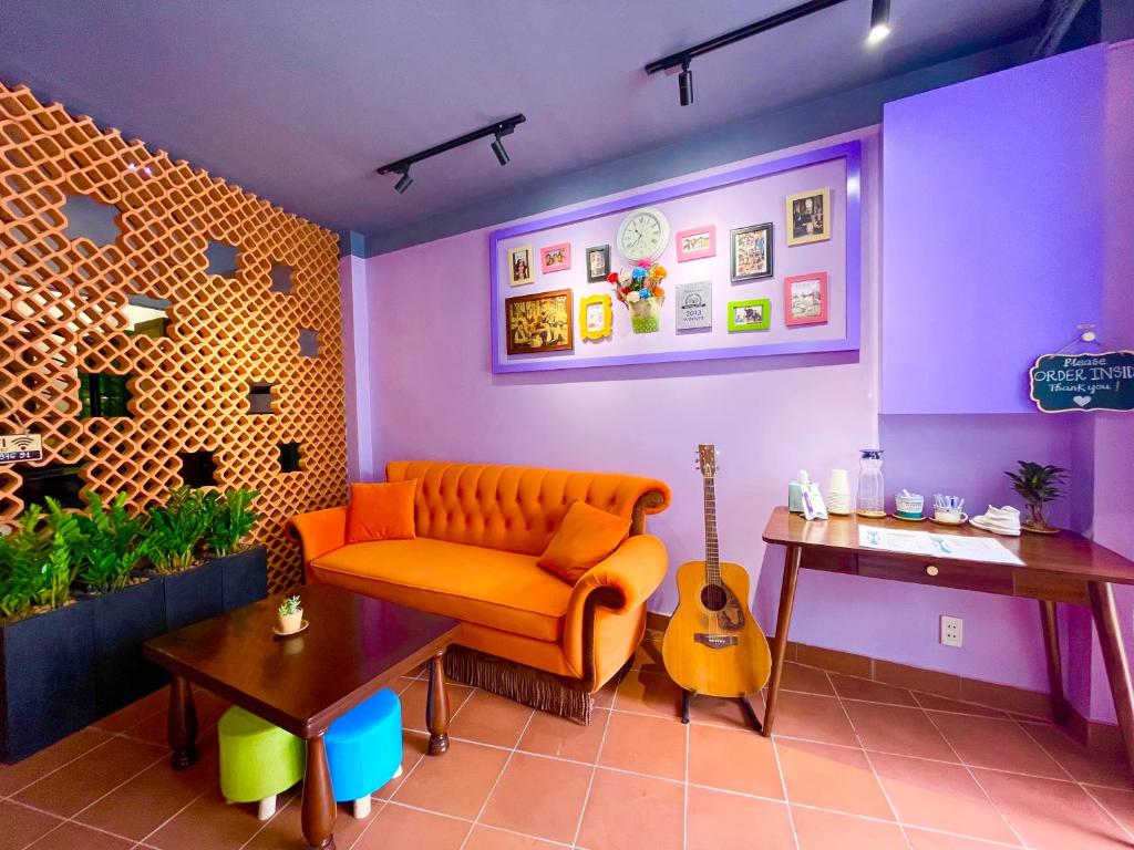 a living room with an orange couch and a guitar at Ahu Hotel & Apartment in Ho Chi Minh City