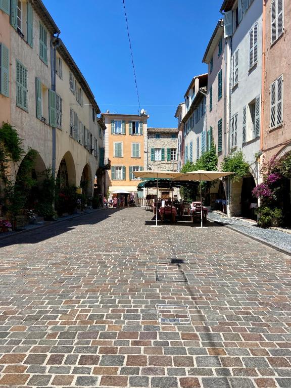 a cobblestone street with tables and umbrellas on it at Appartement Biot Village in Biot