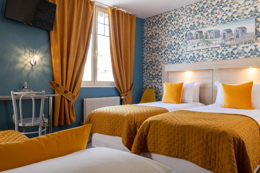 a hotel room with two beds and a window at Hôtel de Lion sur Mer in Lion-sur-Mer