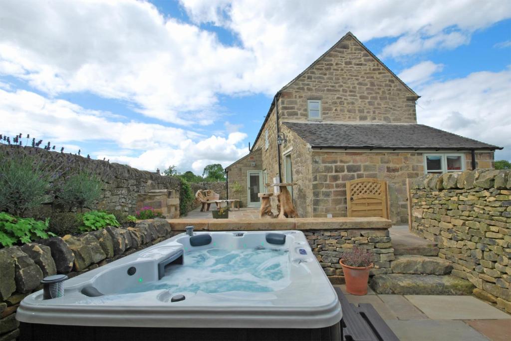 eine Badewanne im Hof eines Steingebäudes in der Unterkunft Heather Cottage in Kirk Ireton