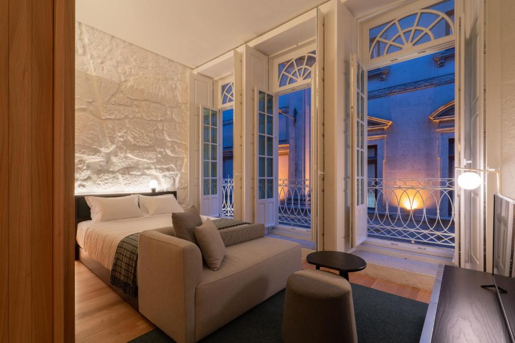 een slaapkamer met een bed, een bank en een raam bij d'ALMA Boutique Hotel in Porto