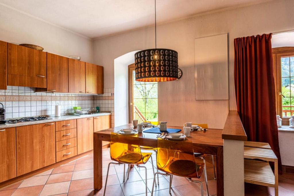 uma cozinha com uma mesa de madeira e cadeiras amarelas em Il Giardino ai Volti 2P, Caldonazzo Ospitar em Caldonazzo