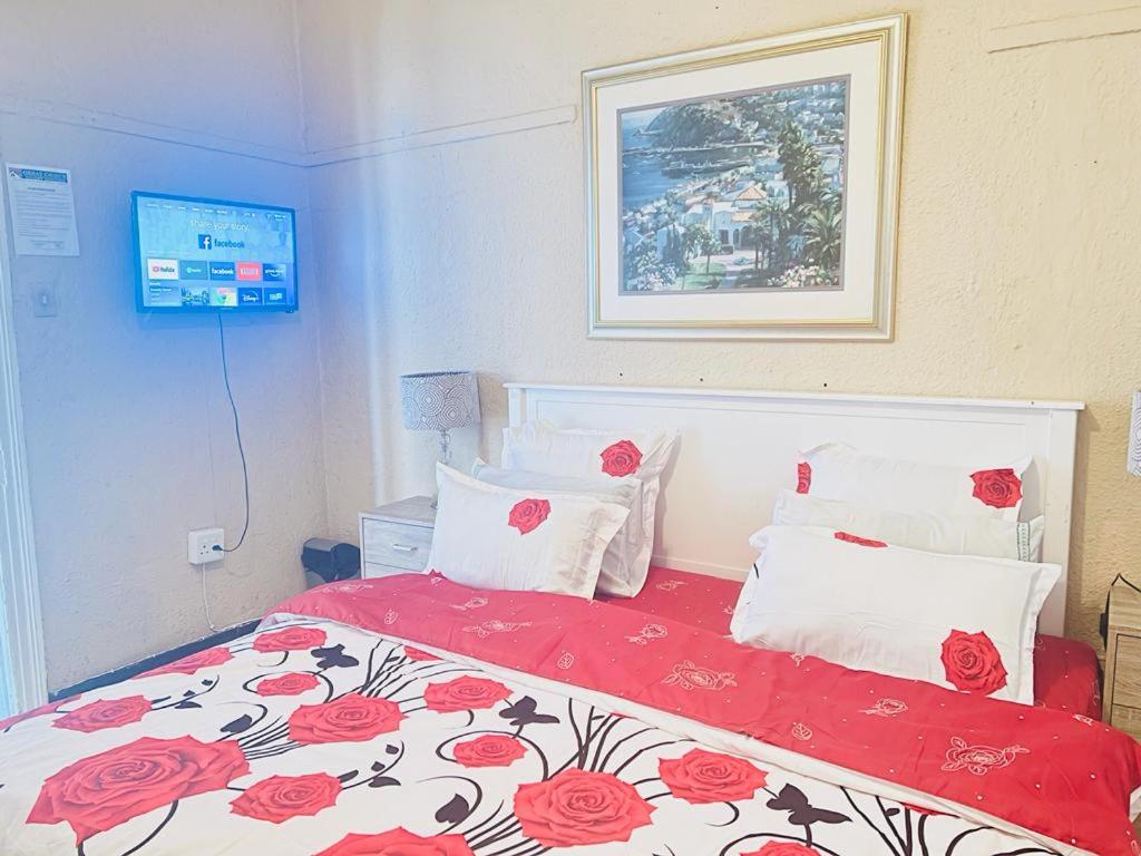 a bedroom with a bed with a red blanket and pillows at Guest Houses Great choice in Cape Town