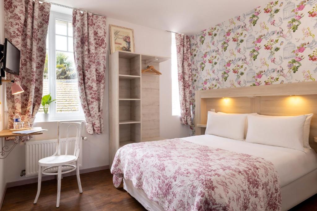 a bedroom with a bed and a chair and a window at Hôtel de Lion sur Mer in Lion-sur-Mer