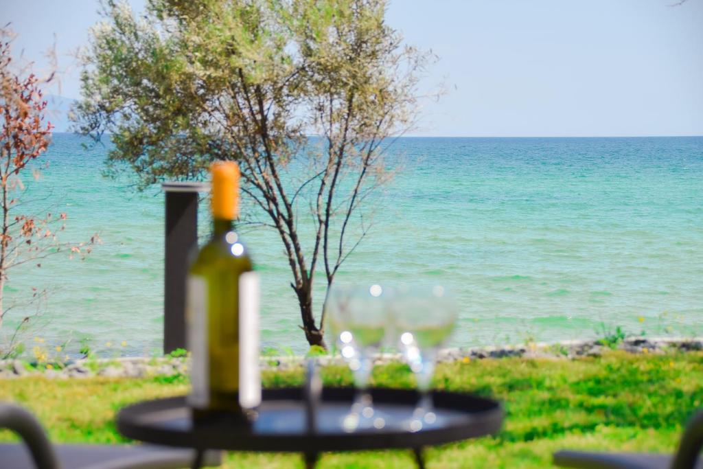 uma garrafa de vinho e copos numa mesa junto ao oceano em Villa SeaWays em PalaiónTsiflíkion