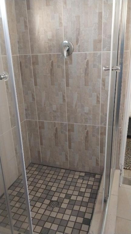 a shower with a glass door and a tiled floor at Seqonoka Villa Accommodation & Events Park in Berea Hills