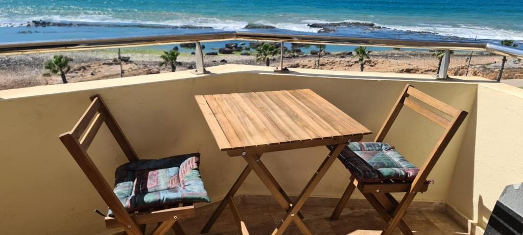 a table and two chairs on a balcony with the beach at Apartement sur la corniche, vue sur mer in Rabat