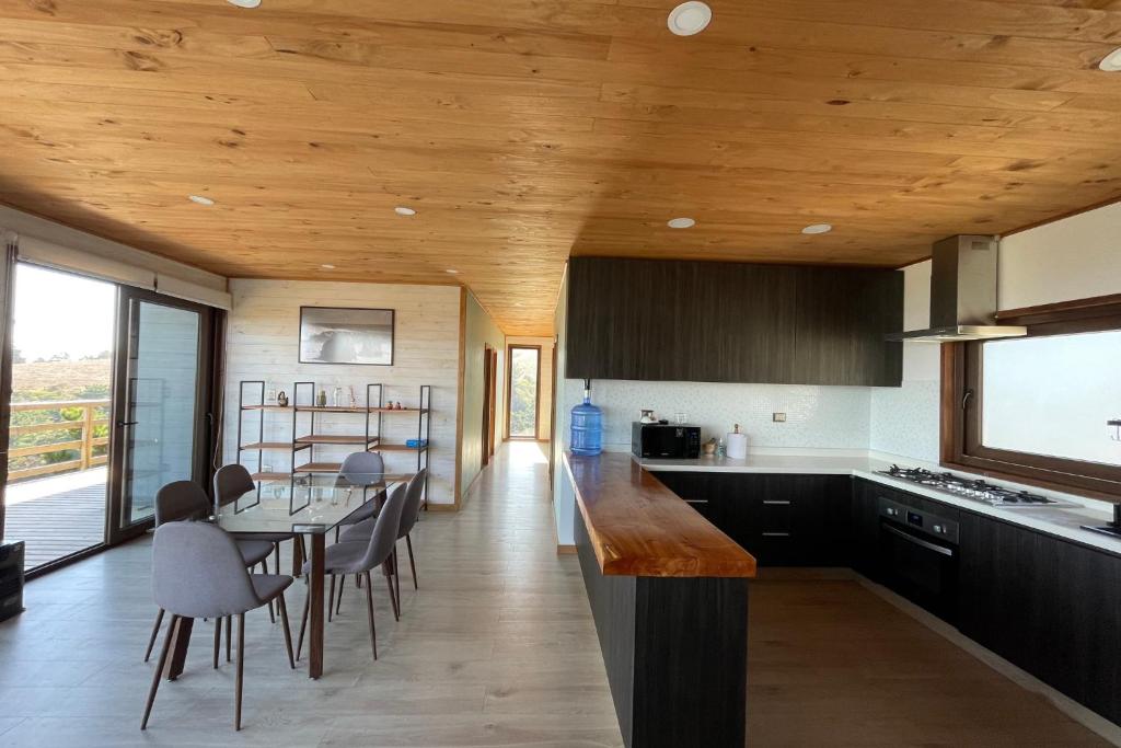 una cucina con soffitti in legno, tavolo e sedie di Casa La Laguna - Pichilemu a Pichilemu
