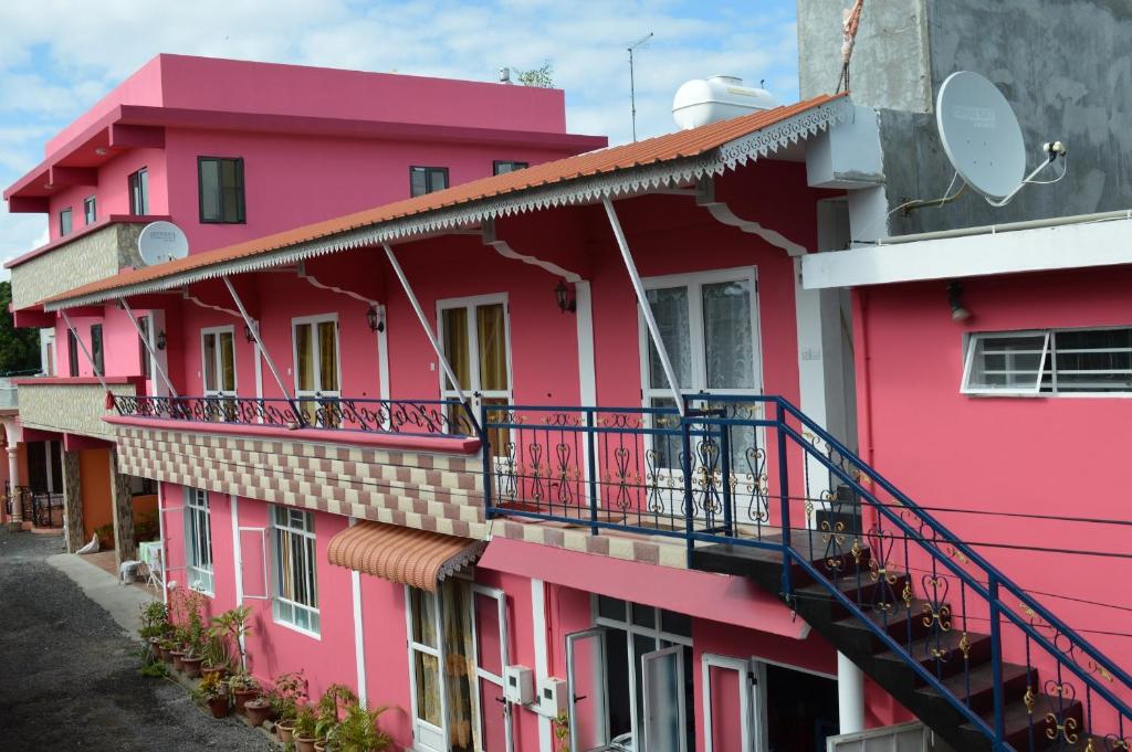 a pink building with a balcony at Paradisia Holidays Mauritius in Trou d'Eau Douce