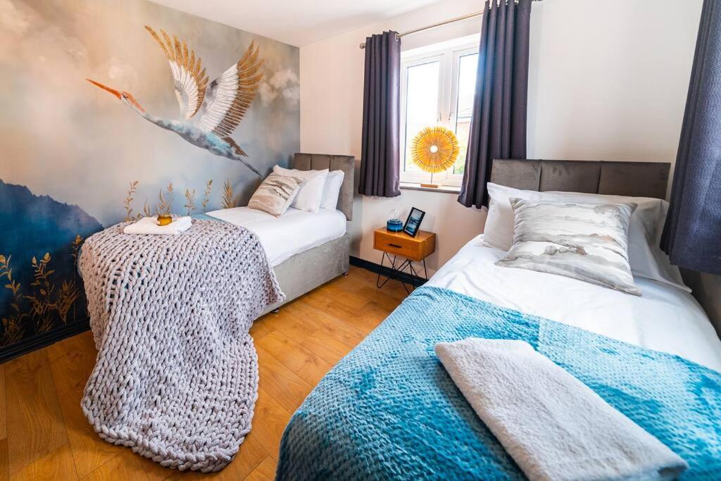 a bedroom with two beds and a table in it at Luxury Detached House with Free Parking, Fast Wifi and Smart TV with Netflix by Yoko Property in Coventry