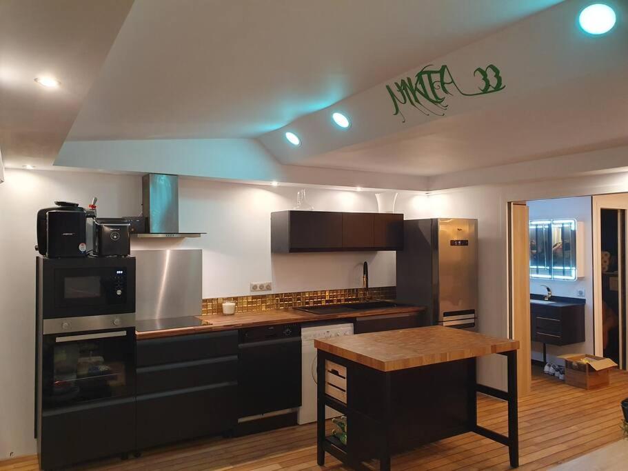 cocina con electrodomésticos en blanco y negro y suelo de madera en Villa-Port Nature-Village Naturiste-1 chambre en Cap d'Agde