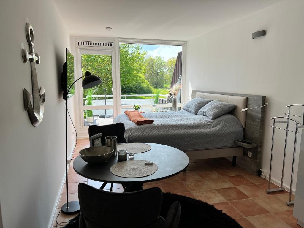 ein kleines Zimmer mit einem Bett, einem Tisch und einem Fenster in der Unterkunft Ferienwohnung 1 Zimmer App Ankerplatz 43 im Olympiazentrum in Kiel
