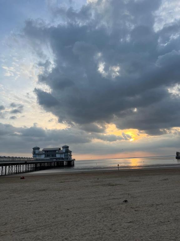 a pier on the beach with a person walking on the sand at Queenswood Hotel in Weston-super-Mare