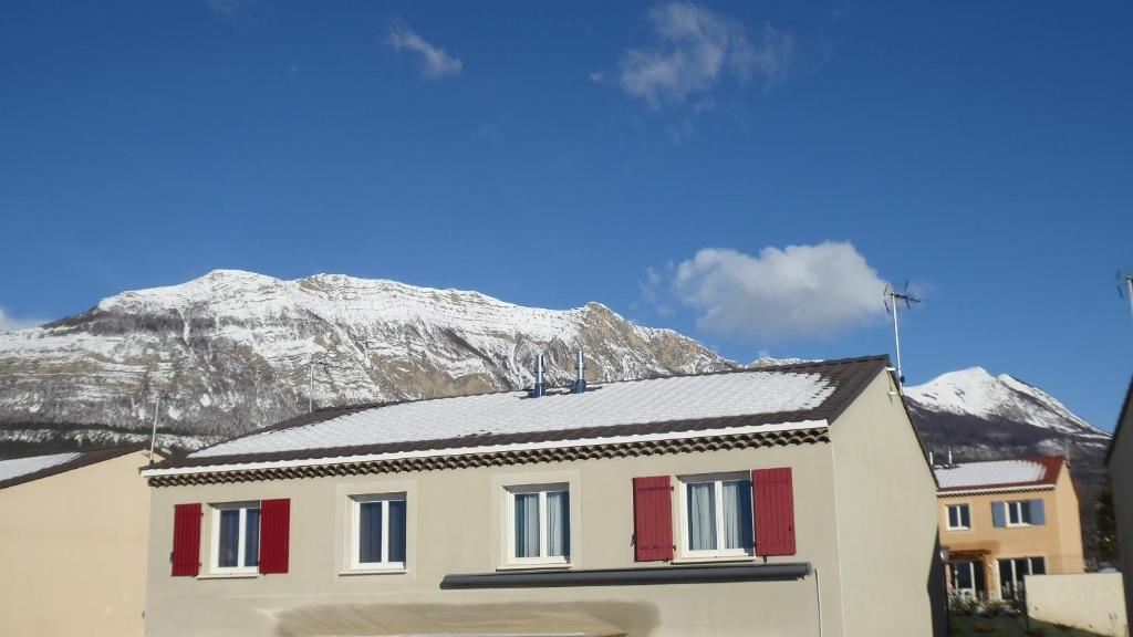 ein Haus mit roten Türen und einem Berg im Hintergrund in der Unterkunft appartement pas loin des montagnes in Gap