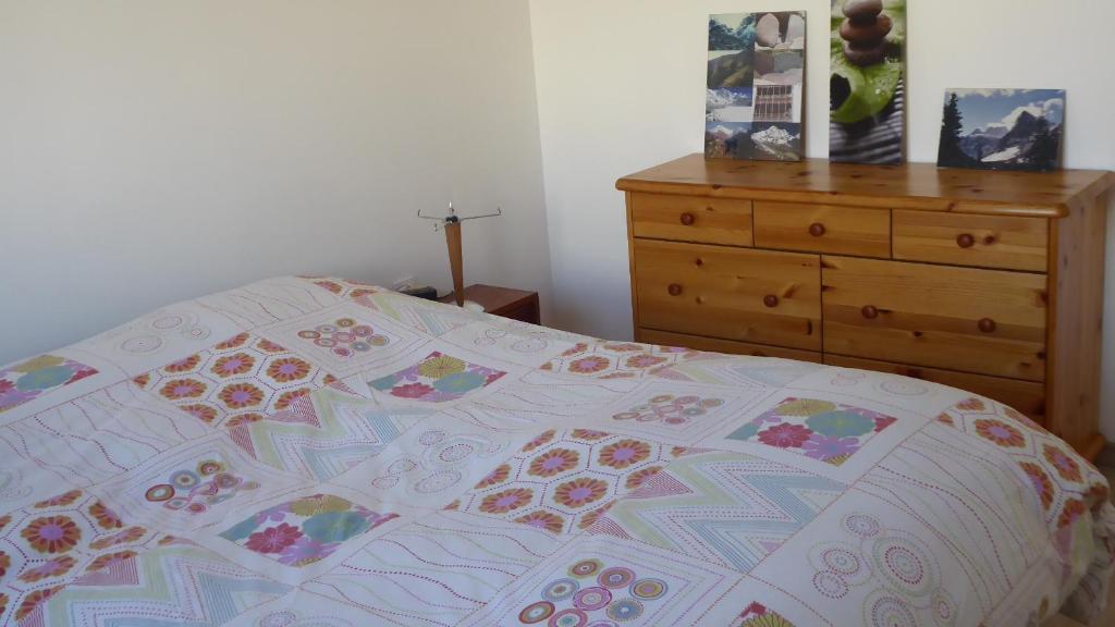 a bedroom with a bed and a dresser with a quilt at appartement pas loin des montagnes in Gap